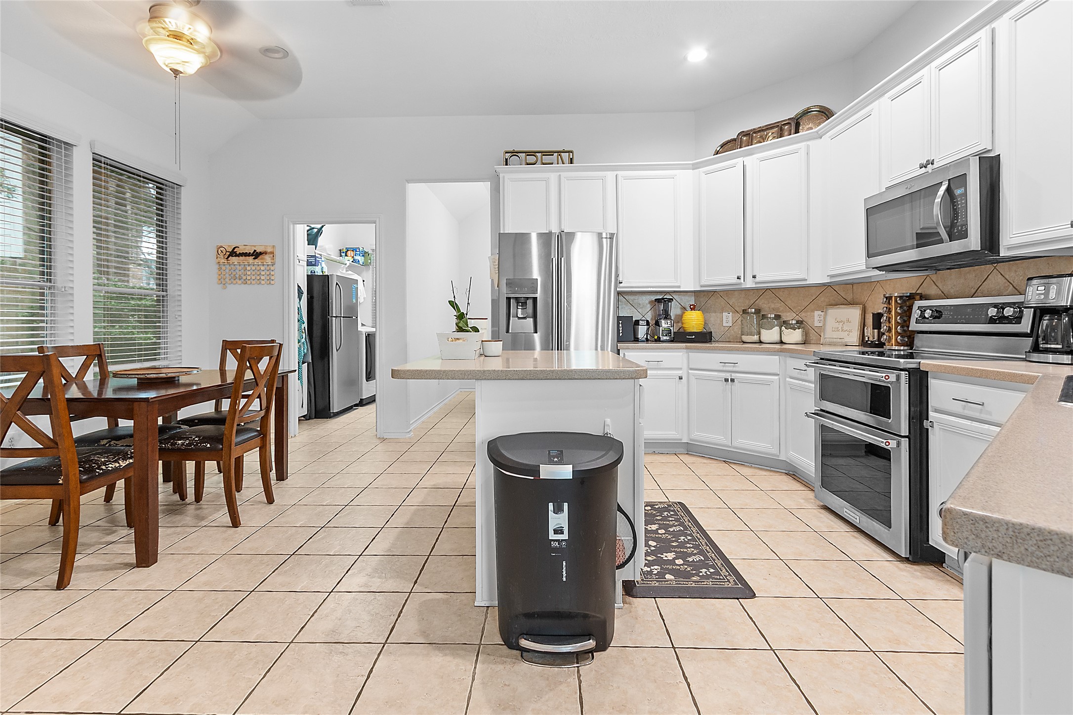 21014 Jessica Rose Lane Spring, TX 77379 - Photo 11 of 30 a kitchen with stainless steel appliances granite countertop a stove top oven a refrigerator a sink dishwasher a dining table and chairs with wooden floor