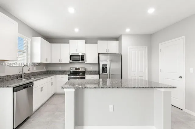 a kitchen with stainless steel appliances granite countertop a refrigerator and a sink