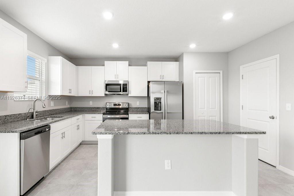 5351 Night Tide Lane Wimauma, FL 33598 - Photo 14 of 22 a kitchen with stainless steel appliances granite countertop a refrigerator and a sink