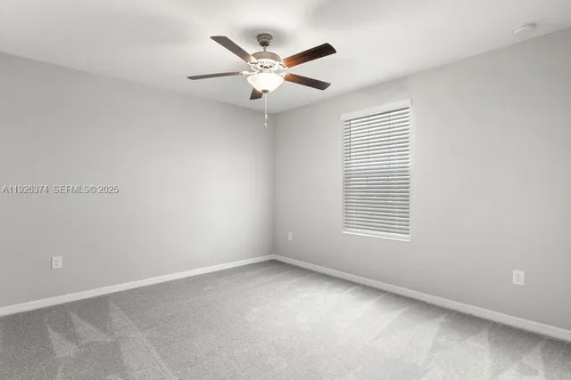 an empty room with a window and a fan