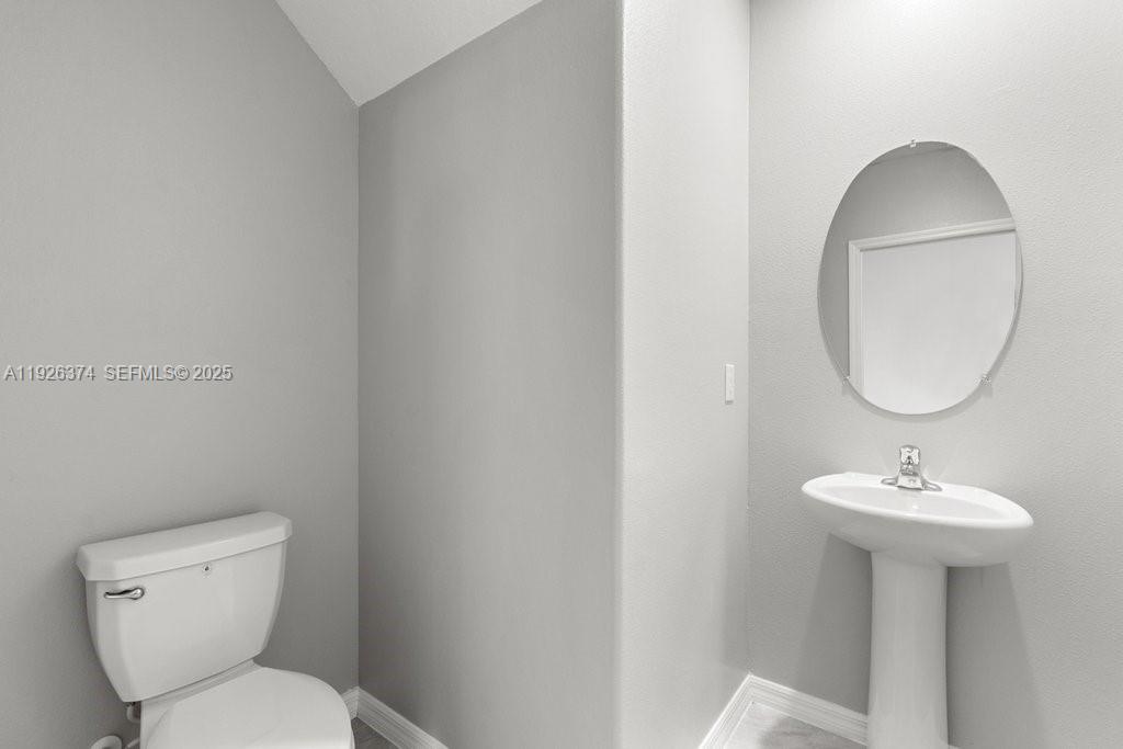 5351 Night Tide Lane Wimauma, FL 33598 - Photo 19 of 22 a bathroom with a toilet sink and mirror