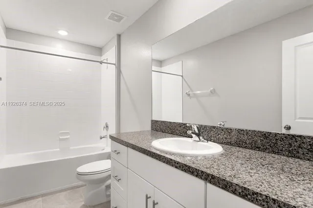 a bathroom with a granite countertop sink a toilet a mirror and shower