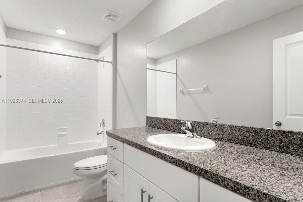 5351 Night Tide Lane Wimauma, FL 33598 - Photo 20 of 22 a bathroom with a granite countertop sink a toilet a mirror and shower