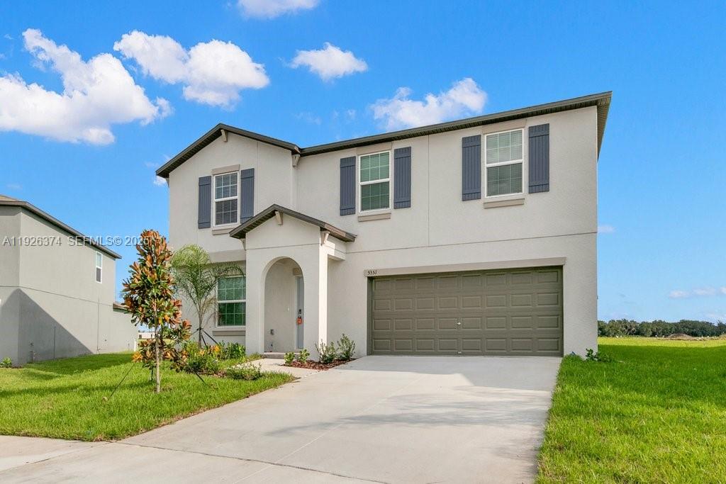 5351 Night Tide Lane Wimauma, FL 33598 - Photo 3 of 22 a front view of a house with a yard and garage