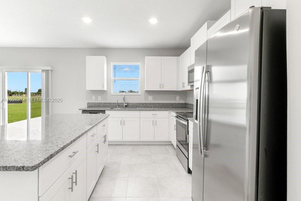 5351 Night Tide Lane Wimauma, FL 33598 - Photo 7 of 22 a kitchen with granite countertop a refrigerator and white cabinets