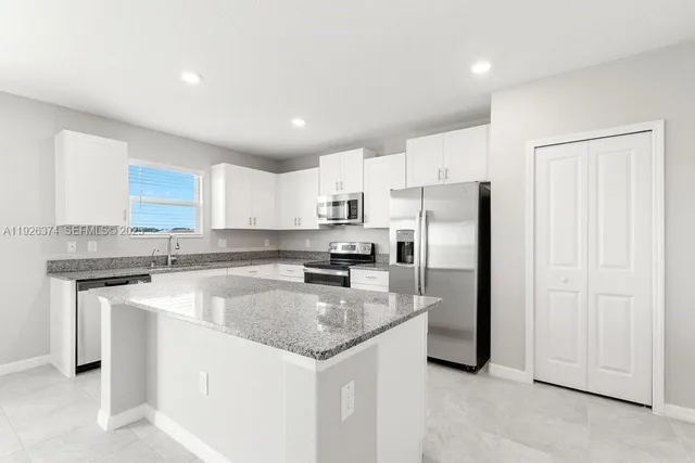 a kitchen with kitchen island a sink stainless steel appliances and white cabinets
