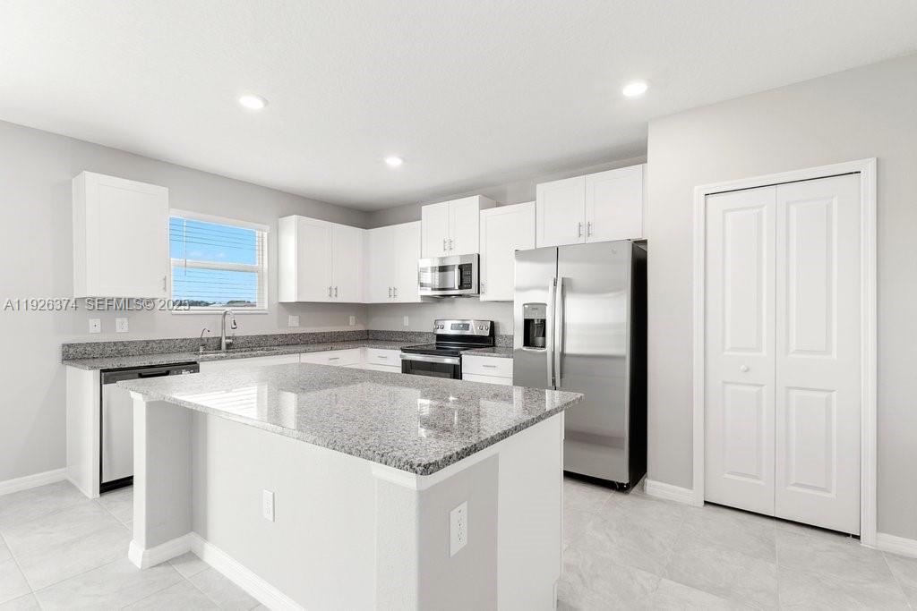 5351 Night Tide Lane Wimauma, FL 33598 - Photo 8 of 22 a kitchen with kitchen island a sink stainless steel appliances and white cabinets