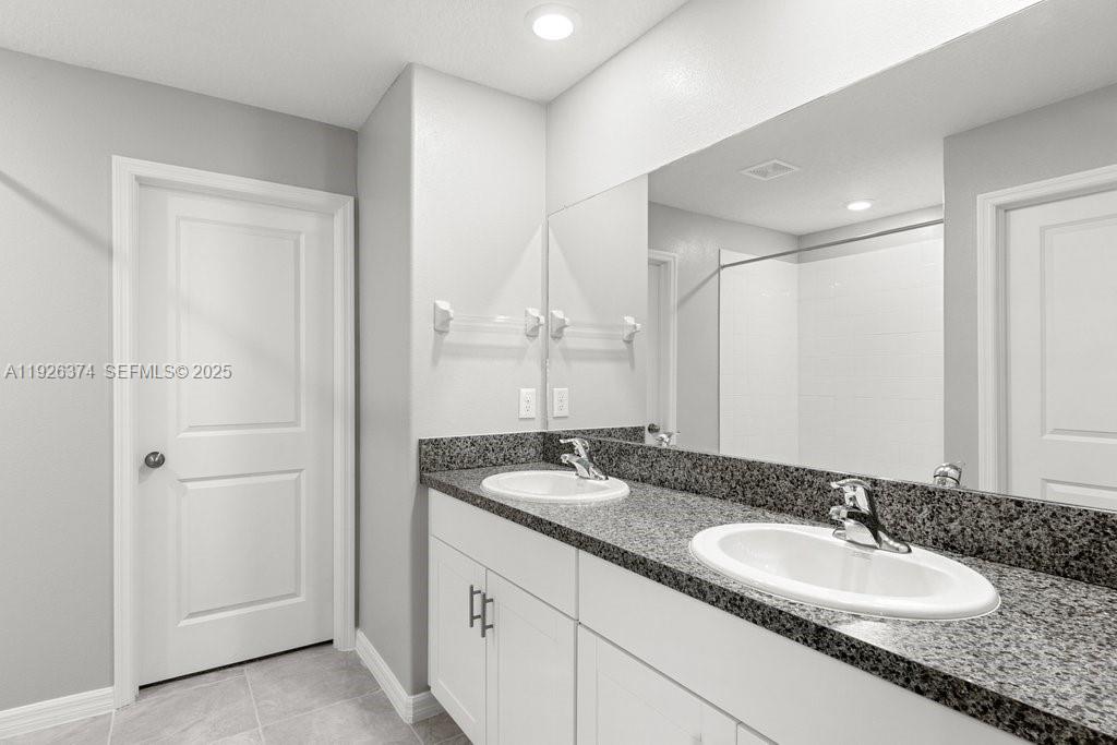 5351 Night Tide Lane Wimauma, FL 33598 - Photo 10 of 22 a bathroom with a granite countertop double vanity sink and a mirror