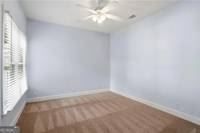 an empty room with a window and a fan