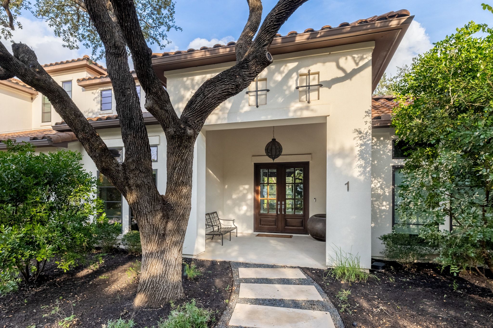 4720 Rockcliff Road, Unit 1 Austin, TX 78746 - Photo 2 of 39 A graceful entry with double wooden doors welcomes visitors, framed by lush landscaping and a mature tree.