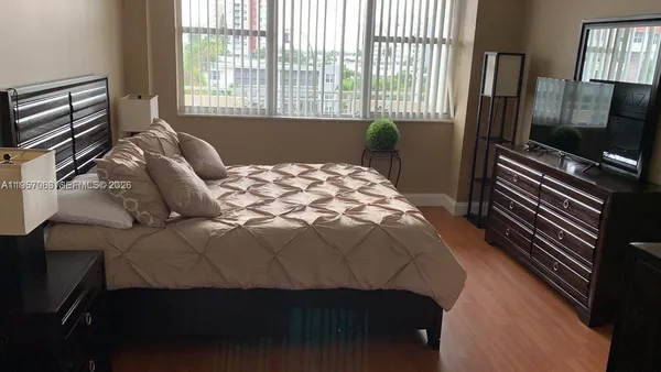 a bedroom with a bed tv and a window
