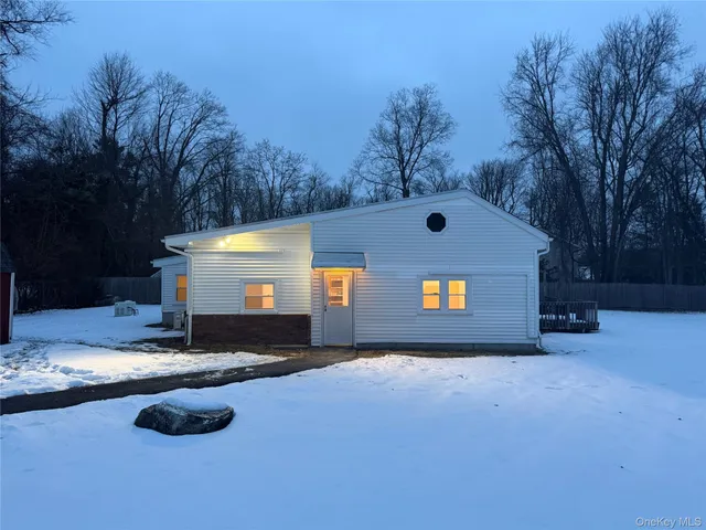 a front view of a house with yard and trees in the background