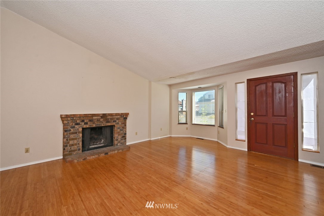 17733 114th Place Southeast Renton, WA 98055 - Photo 3 of 23 an empty room with wooden floor fireplace and windows
