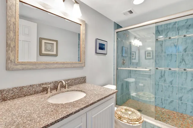 a bathroom with a granite countertop sink a mirror and a shower