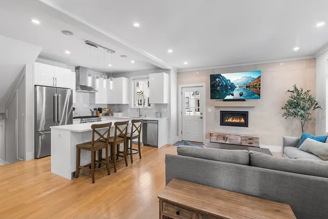 a living room with stainless steel appliances furniture and a kitchen view