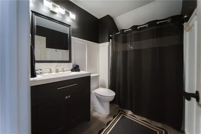 a bathroom with a granite countertop sink a toilet and shower