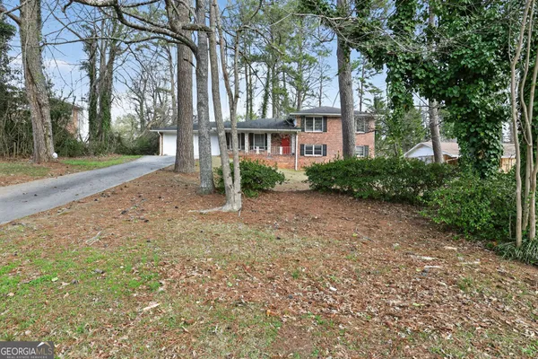 a view of a brick house next to a yard with large trees