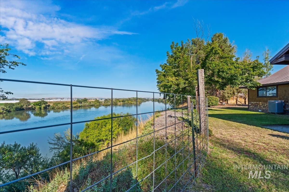 8275 Washoe Road Fruitland, ID 83619 - Photo 33 of 43 Waterfront property featuring a wire fence, verdant foliage, and a stone facade