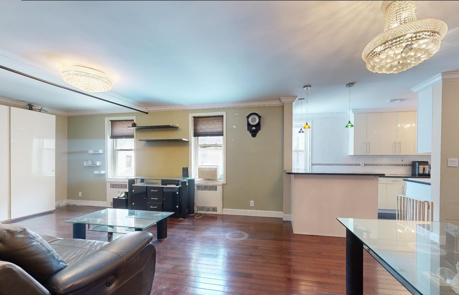 94-10 64th Road, Unit B6 Queens, NY 11374 - Photo 6 of 17 Living room with radiator heating unit, ornamental molding, dark wood finished floors, baseboards, and a chandelier