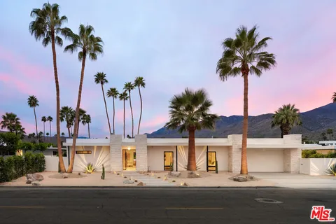 a front view of multiple houses with palm tree