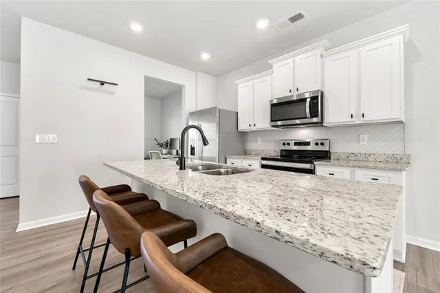 a kitchen with kitchen island granite countertop a sink counter top space appliances and cabinets