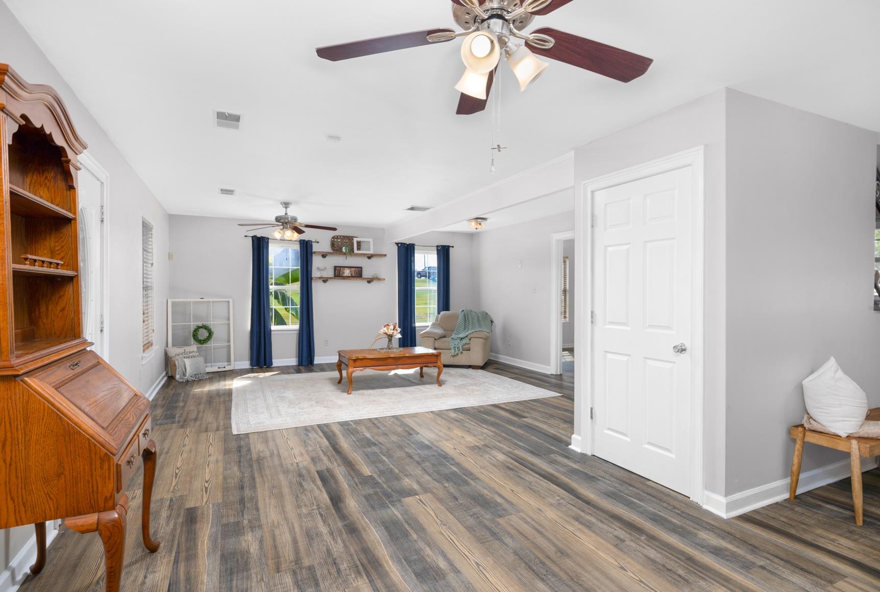 Spacious interior with wood-finish flooring, light grey walls, and multiple ceiling fans