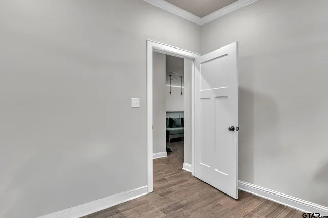 a view of an empty room with wooden floor and closet