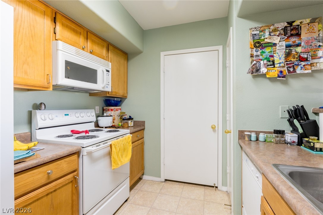 7255 West Sunset Road, Unit 2030 Las Vegas, NV 89113 - Photo 7 of 24 Kitchen featuring white appliances, light countertops, and wood finish cabinetry