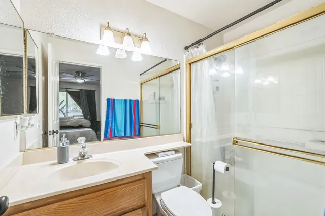 a bathroom with a sink a toilet a mirror and shower