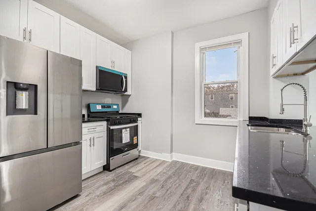 a kitchen with granite countertop white cabinets and sink