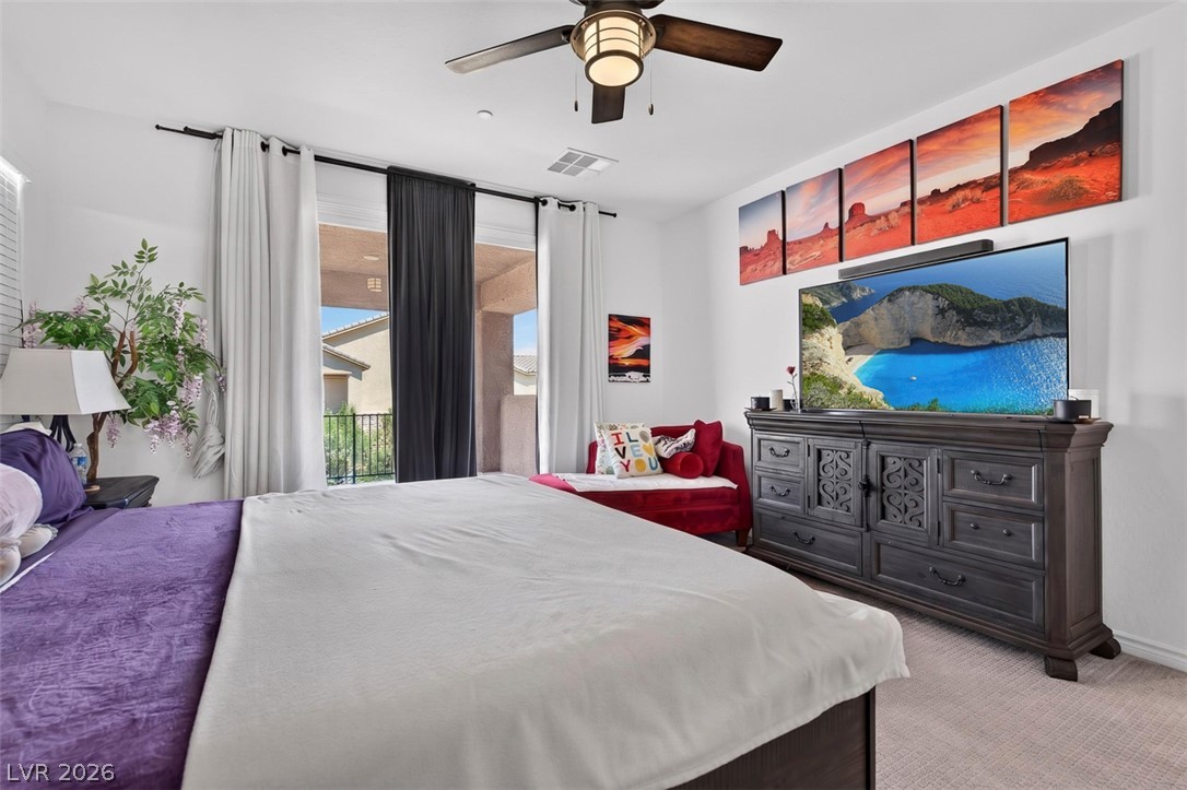 1824 Redland Ridge Street Henderson, NV 89002 - Photo 37 of 69 Natural light floods this spacious bedroom, offering direct access to an outdoor balcony and featuring a modern ceiling fan.