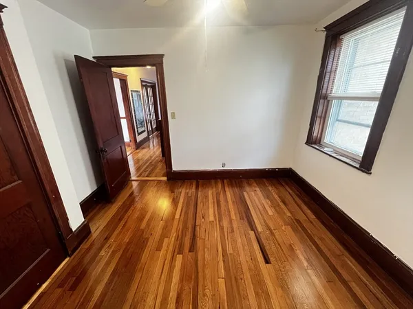 a view of empty room with wooden floor and fan