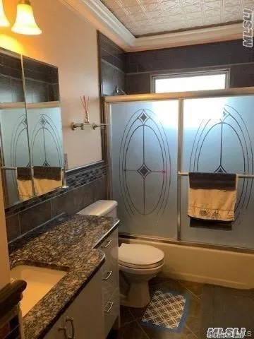 a bathroom with a granite countertop toilet sink and mirror