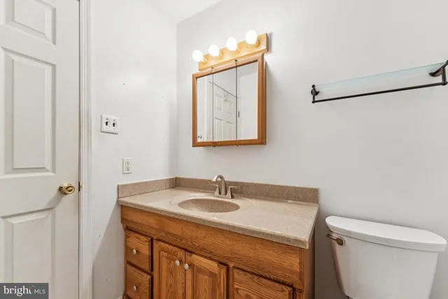 a bathroom with a granite countertop sink toilet and a mirror
