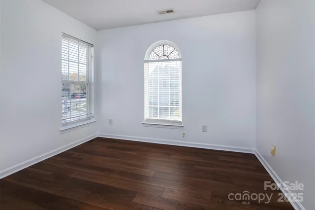 an empty room with wooden floor a exposed radiator and a window