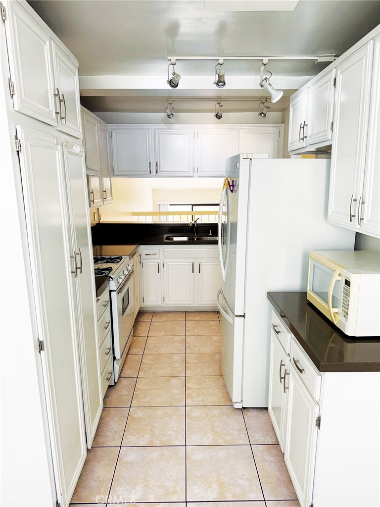 18419 Collins Street, Unit E Tarzana, CA 91356 - Photo 12 of 40 a kitchen with stainless steel appliances a sink and a refrigerator