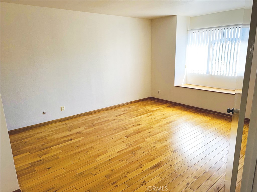 18419 Collins Street, Unit E Tarzana, CA 91356 - Photo 18 of 40 a view of an empty room with wooden floor and a window