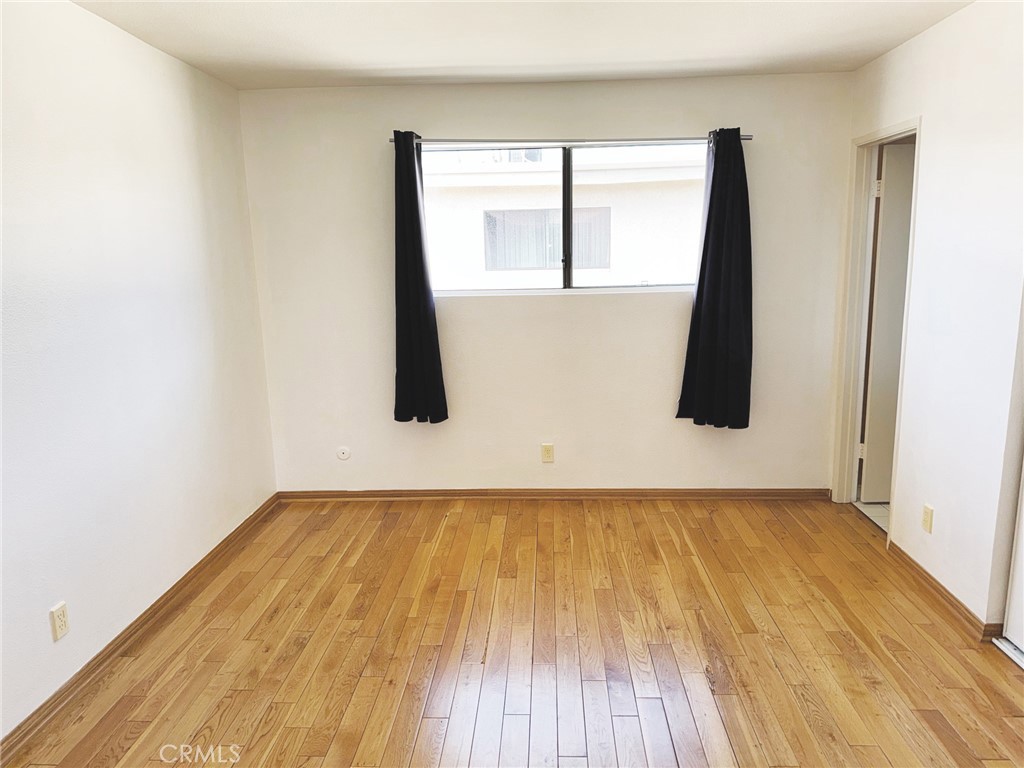 18419 Collins Street, Unit E Tarzana, CA 91356 - Photo 22 of 40 an empty room with wooden floor and a window