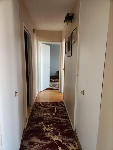 a view of a hallway view with wooden floor and a bathroom
