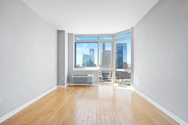 a view of a big room with wooden floor and windows