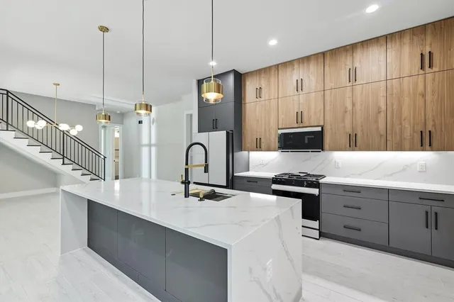 a kitchen with stainless steel appliances kitchen island granite countertop a sink a stove and a refrigerator