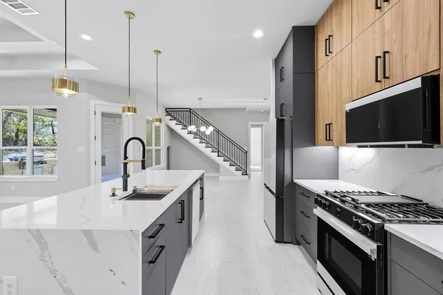 a kitchen with stainless steel appliances granite countertop a sink a stove and a refrigerator