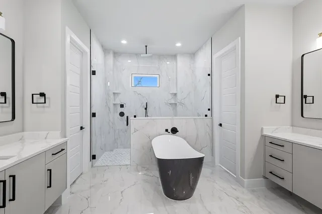 a spacious bathroom with a tub sink shower and mirror