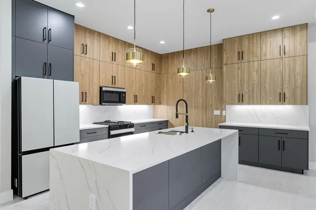 a kitchen with stainless steel appliances a refrigerator a sink a stove and white cabinets with wooden floor