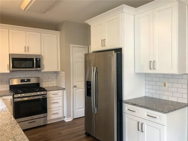 a kitchen with stainless steel appliances granite countertop a stove a sink and a large window