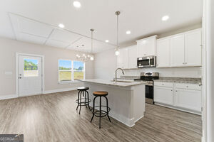 11149 Cornerstone Lane Hampton, GA 30228 - Photo 11 of 29 a kitchen with stainless steel appliances granite countertop a sink a stove a refrigerator and white cabinets with wooden floor