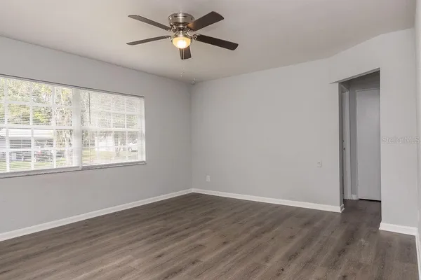 a view of empty room with wooden floor and fan