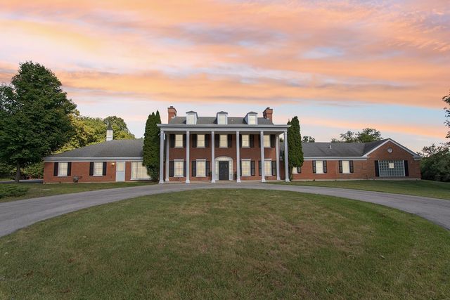 a view of a house with a big yard and large trees