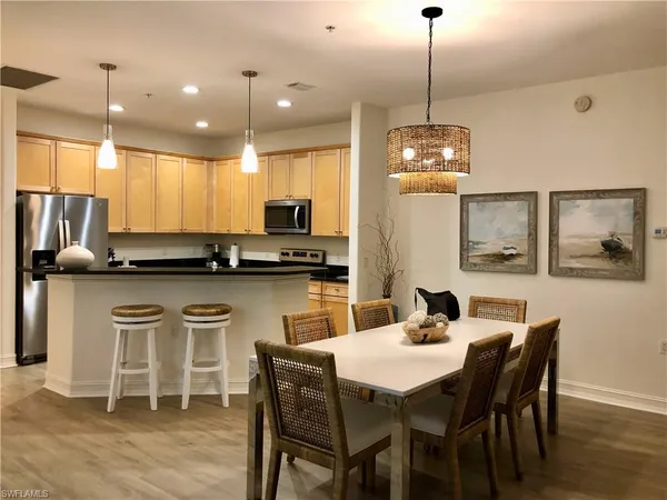 a kitchen with stainless steel appliances kitchen island granite countertop a dining table chairs and white cabinets