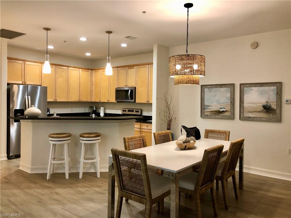 a kitchen with stainless steel appliances kitchen island granite countertop a dining table chairs and white cabinets